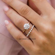 a woman's hand with a diamond ring on top of her finger and the other hand holding an engagement ring