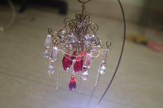 a chandelier with red and clear beads hanging from it's metal stand