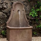 a water fountain in front of a stone wall