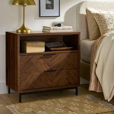 a bedroom with a bed, nightstand and lamp on the side table in front of it