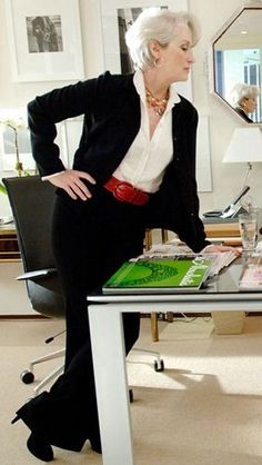 a woman sitting at a desk with her hands on her hips