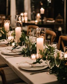 a long table with candles and greenery is set for an elegant dinner or party