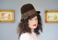 "DESCRIPTION * Vintage hat from 1950s-1960s * women bowler hat design: tall round crown, narrowly curled up brim in the back and on the right    * made of brown wool felt fabric * the hatband is wrapped with a thick grosgrain ribbon and embellished a bow on the side * tag reads \"Electra/ Neumann Endler/ 100% Wool\" CONDITION * the hat has a few indented and insect bite marks on the brim, please see the last photo. * otherwise, the hat shows signs of normal use with minor soiling, discoloration Retro Fedora With Curved Brim For Kentucky Derby, Retro Curved Brim Fedora For Kentucky Derby, Retro Fedora Hats For Kentucky Derby, Retro Short Brim Hat For Kentucky Derby, Vintage Fitted Fedora Mini Hats, Vintage Fedora With Curved Brim For Kentucky Derby, Vintage Brown Cloche Hat For Kentucky Derby, Vintage Brown Brimmed Boater Hat, Vintage Brown Cloche Hat With Flat Brim