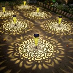 several yellow vases sitting on top of a cement floor covered in light shining through them