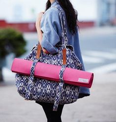 a woman walking down the street carrying a large pink duffel bag on her back