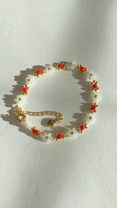 a beaded bracelet with red and white beads is shown on a white surface,