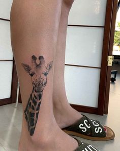 a giraffe tattoo on the leg of a woman