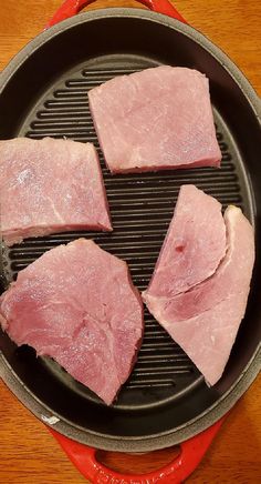 four pieces of meat cooking in a frying pan