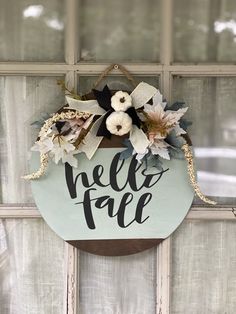 a sign that says hello fall hanging on the side of a window with flowers in it