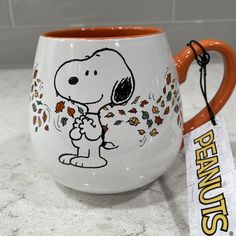 a coffee mug with a charlie brown sticker on it and a peanuts tag hanging from the handle