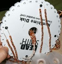 a person holding up a white disc with brown beads on it's sides and the words hills end written in russian