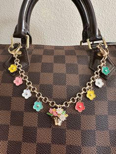 a handbag with flowers and charms on it's chain hanging from the handle