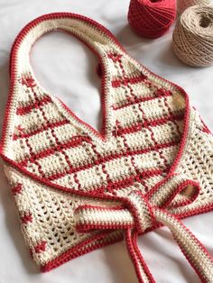 a crocheted bag with red and white stripes on it next to two skeins of yarn