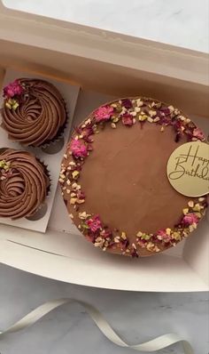 a birthday cake and three cupcakes in a box