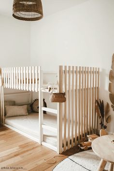 there is a wooden crib in the corner of this room with white walls and wood flooring