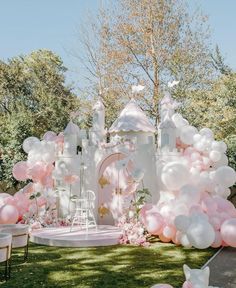 a white castle with pink and white balloons on the lawn at a princess themed birthday party