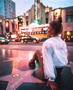 a woman sitting on the hollywood walk of fame