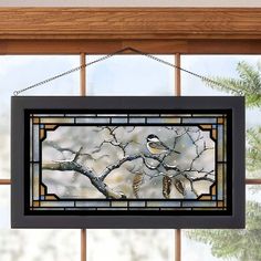 a stained glass window hanging from the side of a window with birds perched on it