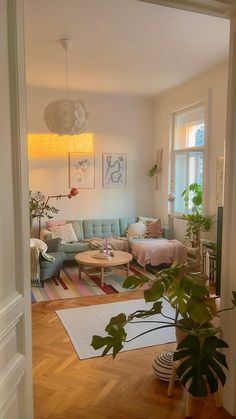 a living room filled with lots of furniture and plants on top of hard wood flooring