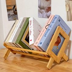 there is a wooden book rack with books in it on the table next to pictures