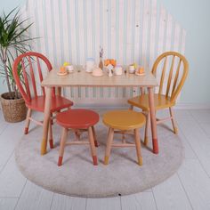 three wooden chairs around a small table with plates and cups on it in front of a striped wall