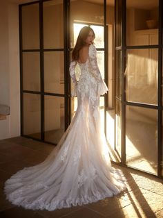 a woman in a wedding dress is standing by an open door with her back to the camera