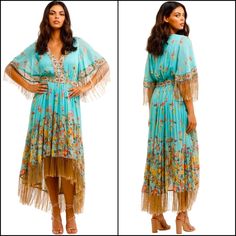 Channel Your Inner Bohemian With The Hendrix Tasseled Dress By Spell! This Beautiful Midi Is Crafted In A Striking Floral Print With A Gold Metallic Thread To Add A Bit Of Glamour. Featuring A V-Neckline, A Flattering Waistband, And A High Low Hem Finished With Feathery Tassels. Hire For Your Next Festival Or Sunset Soiree! * Lined At Bodice * Tiered Skirt * Short Sleeves Finished With Tassels Style This Dazzling Dress With A Wide Strap Sandal And An Oversized Pair Of Sunglasses! Finish The Look With A Relaxed Updo And Minimal Glowy Makeup. Brand New With Tags 49% Organic Cotton, 48% Viscose, 3% Metallic | Lining: 100% Viscose Colours: Multi, Print Recommended For: Daytime Event, Spring Fringe Maxi Dress, Festive V-neck Dress With Tassels, Bohemian V-neck Fringe Dress, Festive Maxi Dress With Tassels, Festive Tassel Maxi Dress, Spring Bohemian Midi Dress With Fringe, Bohemian Midi Dress With Fringe For Spring, Spring Bohemian Fringe Midi Dress, Bohemian Fringe Midi Dress For Spring