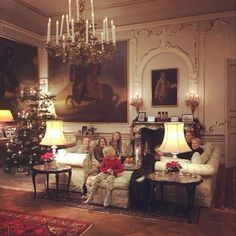 three women sitting on couches in a living room with christmas tree and chandelier