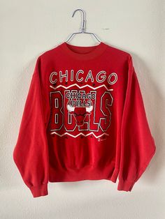 "Vintage 1990's Chicago Bulls Heavyweight Sweatshirt Pullover style, bright red, super cozy. In mint condition, possibly never worn. Graphic super vibrant, no stains or holes.  Officially Licensed product of the NBA - Team Hanes production. Tag size Men's XL maybe more like a modern day Large. See measurements to be sure of fit.  Measurements lying flat: pit to pit: 24\" shoulders: 22.5\" sleeve: 22.5\", length: 25\"" Red Oversized 90s Tops, Oversized 90s Red Top, 90s Red Cotton Sweatshirt, Retro Red Top With Ribbed Cuffs, Red Graphic Sweatshirt For Sports Events, Red Graphic Print Sweatshirt For Sports Events, Retro Red Graphic Print Sweatshirt, Retro Red Sweatshirt For Streetwear, Retro Red Sweatshirt With Graphic Print