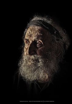 an old man with a long beard and wearing a black shirt is staring into the distance