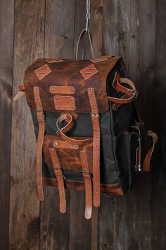 a brown and black backpack hanging from a chain on a wooden wall with chains attached to it