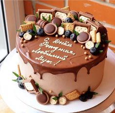 a birthday cake with chocolate frosting and candies on the top is decorated with cookies