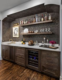 a kitchen with wooden floors and shelves filled with bottles, glasses, and liquors