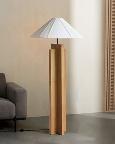 a lamp that is on top of a wooden stand in front of a couch and chair