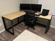 a corner desk with two computer monitors and a laptop