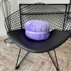 a purple pillow sitting on top of a black chair next to an iron wire basket