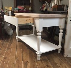 a white table with two drawers on the bottom and an open drawer underneath it in a living room