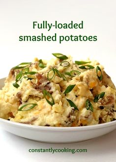 a white bowl filled with mashed potatoes topped with green leaves