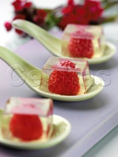 four small desserts on spoons with flowers in the backgroung area