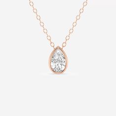 a rose gold necklace with a pear shaped diamond in the center, on a white background