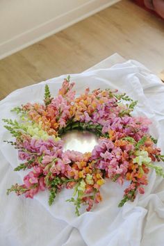 a bunch of flowers that are sitting on a white table cloth in the middle of a room