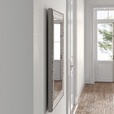 an empty hallway with two mirrors on the wall and one door open to another room