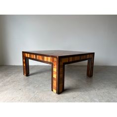 a wooden table sitting on top of a cement floor next to a white wall in an empty room