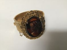 "Free shipping to the USA and Canada. A remarkable Victorian style cameo cuff bracelet.  Simply exquisite with stunning details on this beautiful bracelet.  The clasp is a hinged slide in perfect working condition and has a safety chain.  The cameo is an early celluloid and a wonderful piece of vintage jewelry. Measurements: 7\" circumference  1\" band width Cameo: 1 5/8\" 1 1/4\"" Antique Evening Bracelets, Antique Cuff Bracelet For Formal Occasions, Elegant Cabochon Cuff Bracelet For Formal Occasions, Elegant Oval Cabochon Cuff Bracelet, Antique Hinged Bracelet For Formal Occasions, Antique Hinged Cuff Bracelet For Formal Occasions, Antique Hinged Bracelets For Formal Occasions, Vintage Cameo Bracelet Jewelry, Antique Oval Cameo Bracelet