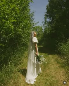 a woman in a wedding dress is walking through the woods