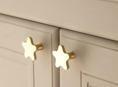 two white cupboards with gold handles and knobs on each side, one in the shape of a star