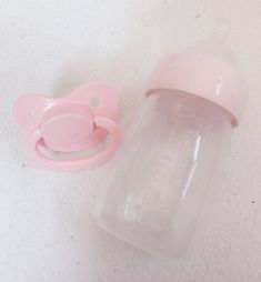 a pink baby bottle with a pacifier next to it