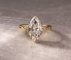 a yellow gold engagement ring with a pear shaped diamond in the center and side stones