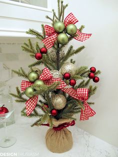 a small christmas tree with red and green ornaments in a burlocked bag