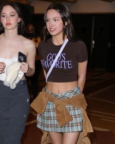 two young women are walking down the street wearing skirts and t - shirts with slogan go's favorite on them